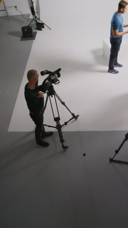 Vertical-Video-Overhead-Shot-Of-Actors-Rehearsing-Movie-Or-Video-Scene-In-Studio-With-Film-Camera-And-Sound-Crew-1